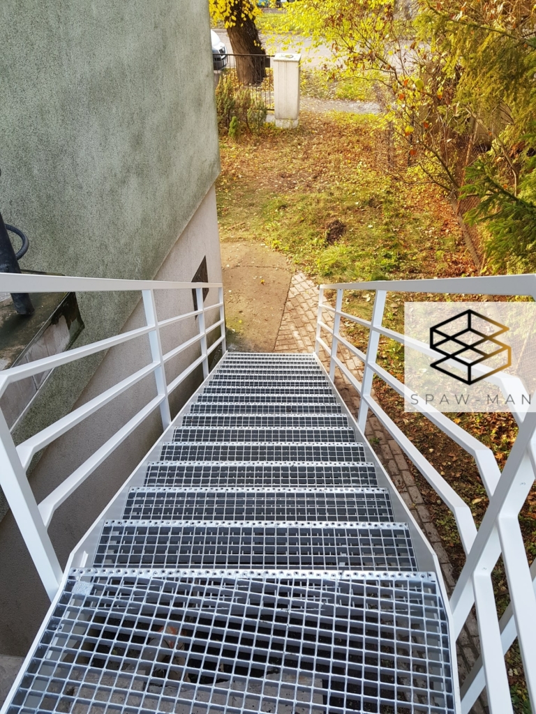 Stalowe schody zewnętrzne ze stopniami z kraty wema, pełnymi policzkami oraz balustradą z poziomym wypełnieniem.